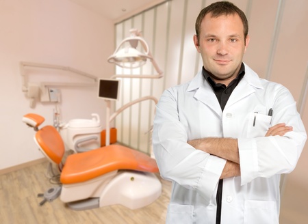 Male dentist standing in a modern dental clinicの写真素材