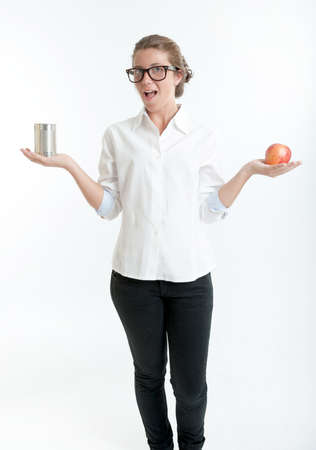 Young woman holding an apple in one hand and a tin in anotherの写真素材