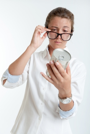 Young woman inspecting an aluminum can through her glassesの写真素材