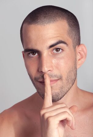 Young man putting a finger on his lipsの写真素材