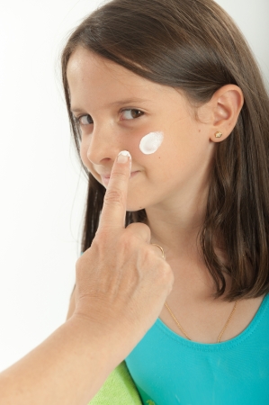 Mother applying sunscreen to her young girlの写真素材