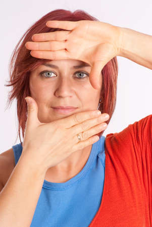 Red haired woman framing her face with her handsの写真素材