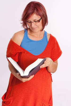 Red haired woman with glasses holding a bookの写真素材