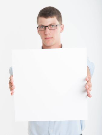 Young man wearing glasses holding a blank square, perfect for inserting your own messageの写真素材