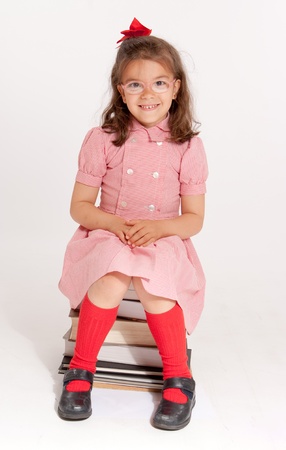 
Little girl with glasses and a happy funny expression sitting on a pile of books
の写真素材
