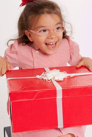 
A little girl with a happy expression holding big red and white present
の写真素材