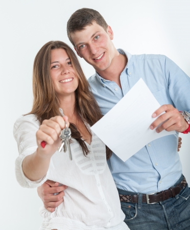 Young couple holding a document and a bunch of keysの写真素材