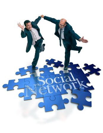 Humorous shot of a pair of running businessmen on a puzzle with the word social networkの写真素材