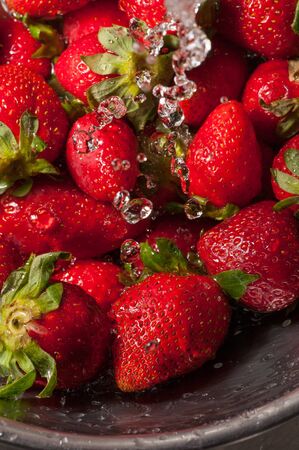 Macro shot on water falling on a group of strawberriesの写真素材