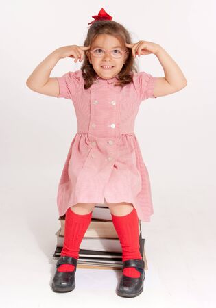 
Little girl with glasses and a happy funny expression sitting on a pile of books
の写真素材