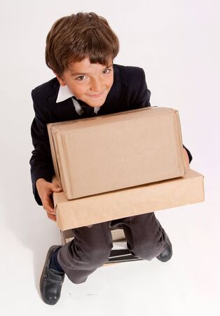 
Little schoolboy with a mischievous expression carrying heavy boxes
の写真素材