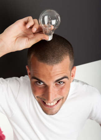 Man with a happy eureka expression holding a light bulbの写真素材
