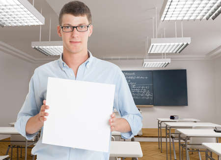 Young man holding a blank board in a classroomの写真素材