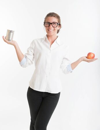 Young woman holding an apple in one hand and a tin in anotherの写真素材