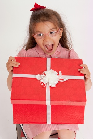 
A little girl sitting on a pile of books opening the lid of a big present
の写真素材