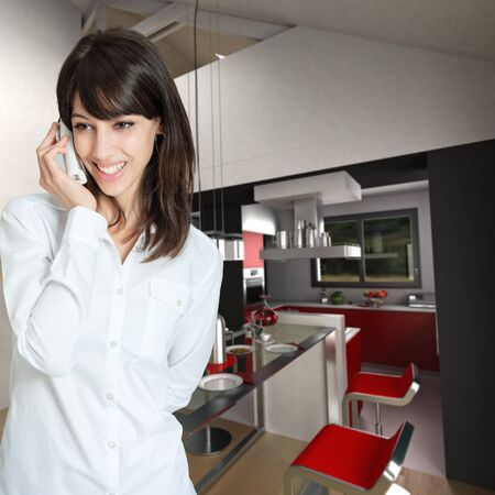Young woman phoning at home, by the kitchenの写真素材