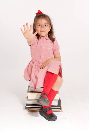 
Little girl with glasses and an stopping gesture sitting on a pile of books
の写真素材