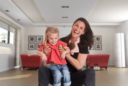 

Cheerful mother holding a cute blonde little girl in a living room
の写真素材