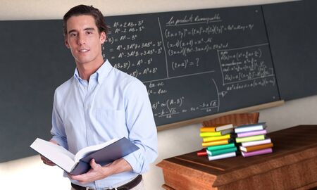 Young male teacher holding a book in a maths classroomの写真素材