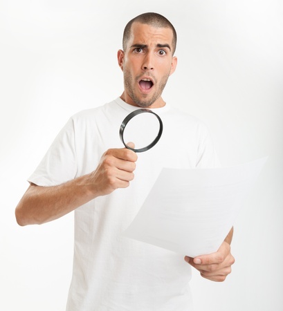 Young man reading a document through a magnifying glass with a shocked expressionの写真素材