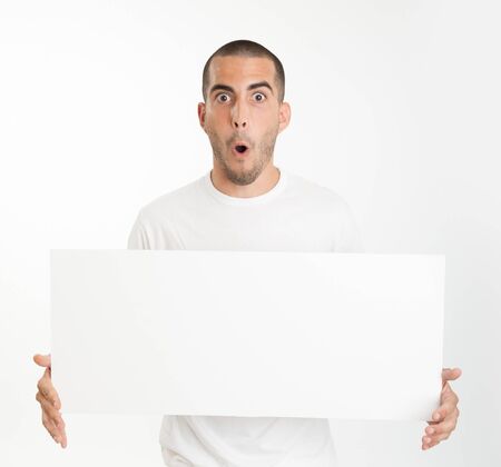 Expressive young man holding a blank board ideal for inserting your own messageの写真素材