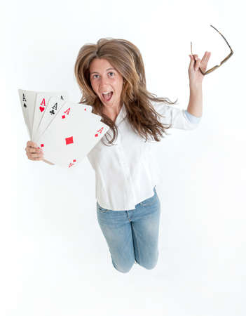 Young woman jumping with joy holding four aces in her handsの写真素材