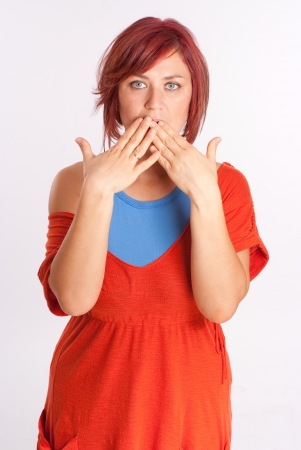 Red haired woman embarrassed covering her mouthの写真素材