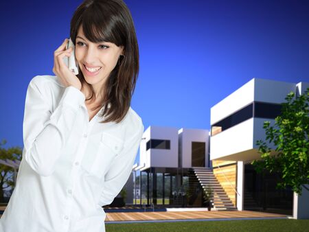 Young woman phoning outside a beautiful modern villaの写真素材