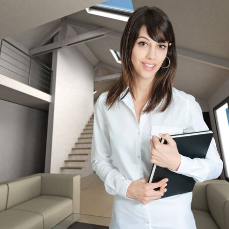 Young woman holding a book standing on a home interiorの写真素材