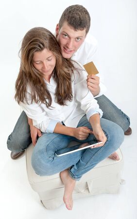 Young couple sitting together with a tablet pc and a credit cardの写真素材