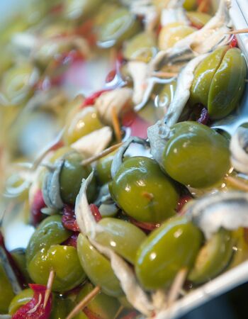 A tray with tapas consisting of olives, anchovies and pickles on skewersの写真素材