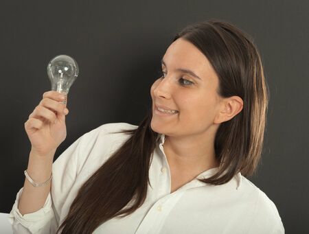 Woman holding a light bulb with a happy expressionの写真素材
