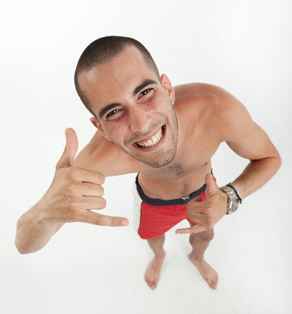 Aerial view of a young man in swimming trunks doing the shaka signの写真素材