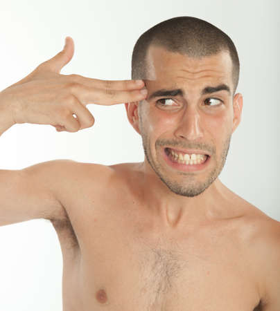 Young man pointing his fingers to his templeの写真素材