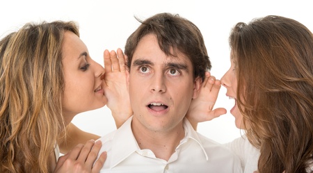 Two girls whispering in the ears of a young manの写真素材