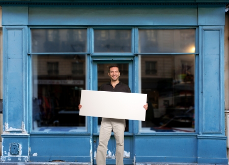 Man standing with a blank sign by a storeの写真素材
