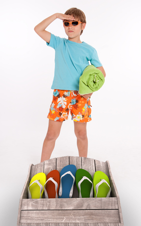 Young boy in beach wear and a group of colorful flip-flopsの写真素材