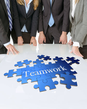 Meeting with people around a table with a puzzle with the word teamworkの写真素材