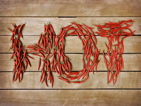 3D rendering of the word hot formed with chili peppers on a wooden backgroundsの写真素材