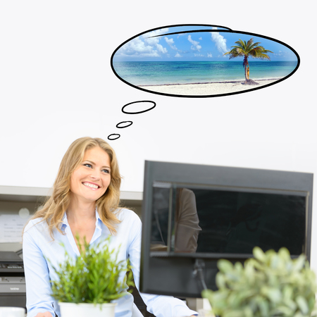 Woman dreaming of her vacation trip at workの写真素材