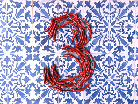 3D rendering of number three formed by chili peppers on a blue and white tiled backgroundの写真素材