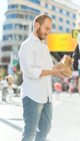 Man on the street checking a boot on a shoeshopの写真素材