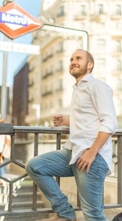 smiling man leaning on the metro entrance rail in Madridのeditorial素材