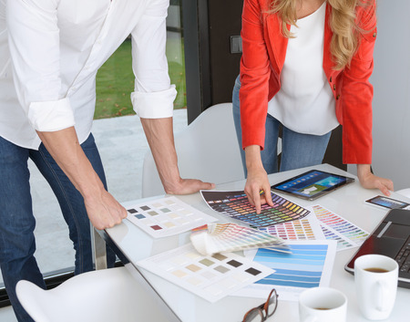 Man and woman in an office surrounded by color charts, material samples and technology