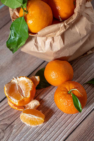 Paper bag with freshly picked mandarines on a wooden surfaceの写真素材