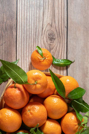 Basket with freshly picked mandarines on a wooden surfaceの写真素材