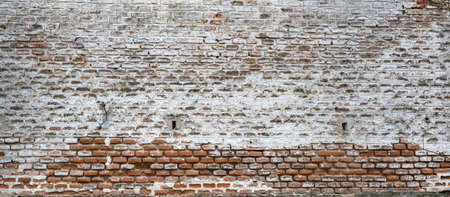 Old brick wall with peeling white paint