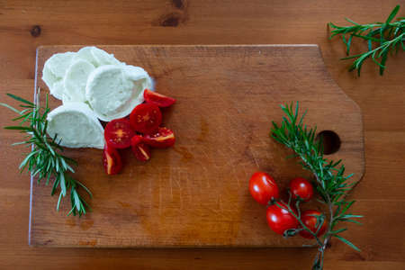 Mediterranean chopping board with tomatoes, mozzarella and rosemaryの写真素材