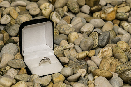 Ring in a jewelry box on background of small pebbles for texture and wallpaperの写真素材