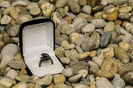 Ring in a jewelry box on background of small pebbles for texture and wallpaperの写真素材